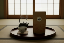 Load image into Gallery viewer, A brown kraft paper stand-up pouch with a white circular sticker reading 'chagama' and a black teapot logo, standing on a wooden surface against a light gray wall.